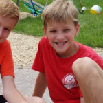 couple of kids smiling with craft in hand