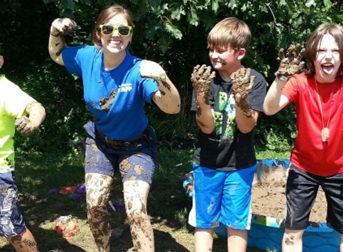 Counselor and three kids posing covered in mud