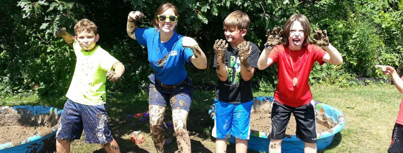 Counselor and three kids posing covered in mud
