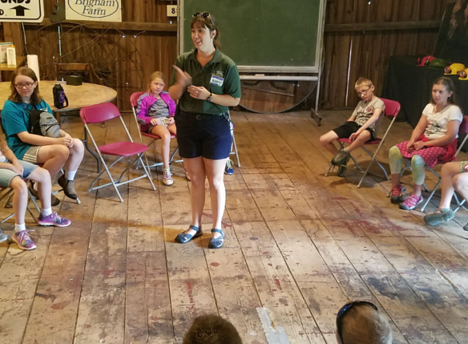 Photo of educator surrounded by kids in barn