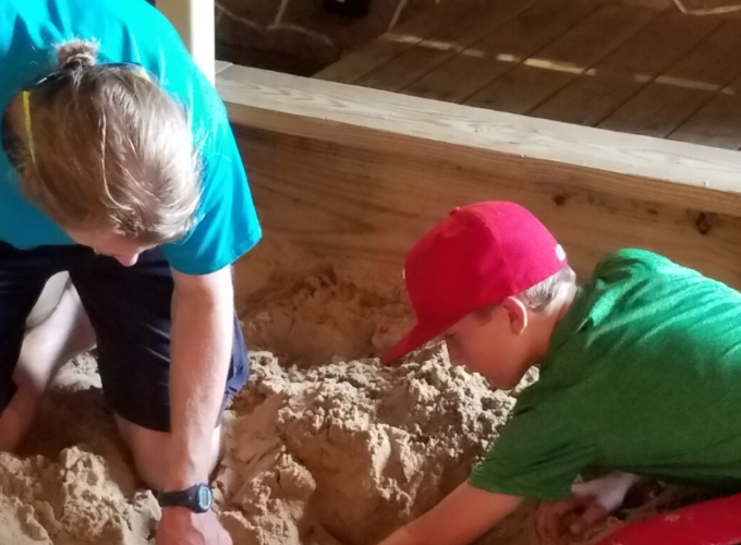 Teacher and kid playing in sand pit