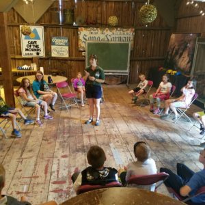 Photo of educator surrounded by kids in barn
