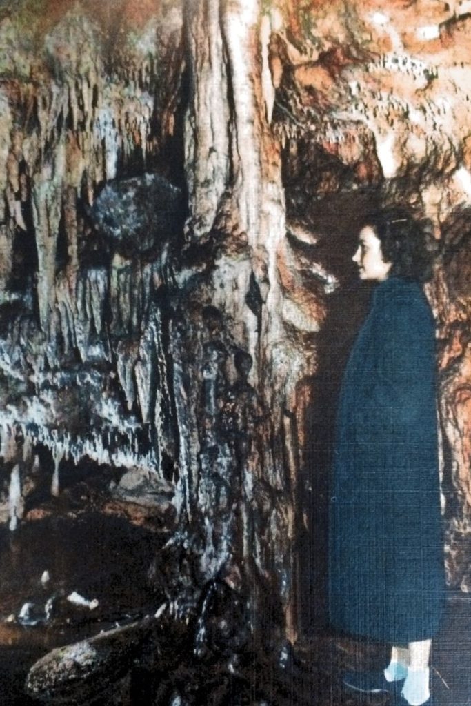 Woman in a winter coat looking at cave formations