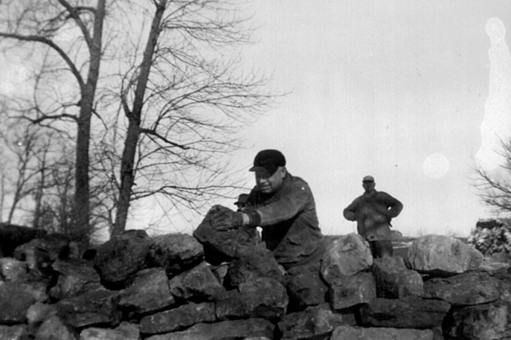 Man in the 1940s rearranging limestone rocks while another man just watches. The start of an important place in wisconsin history