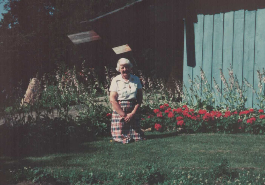 Woman on knees posing in front of flower beds