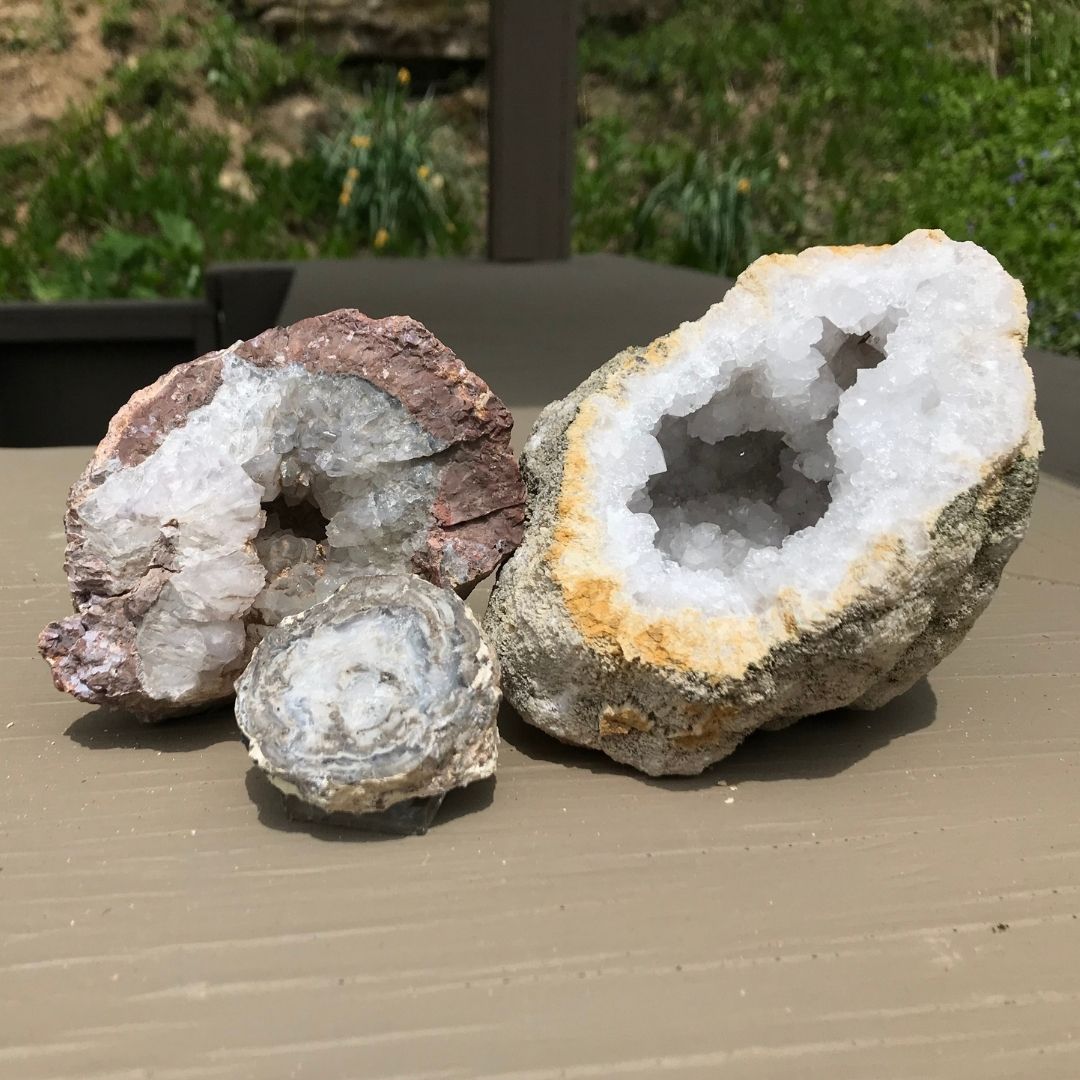 A set of three geodes halves, cracked open to display an array of white crystals inside.