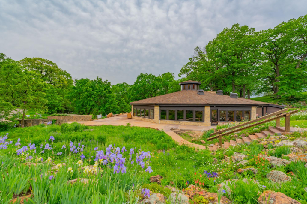 A bright photo of a round building with prairie flowers and gardens in the foreground.