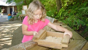 A photo of our Gem Mine with Child sifting through the sand for rocks or fossils.